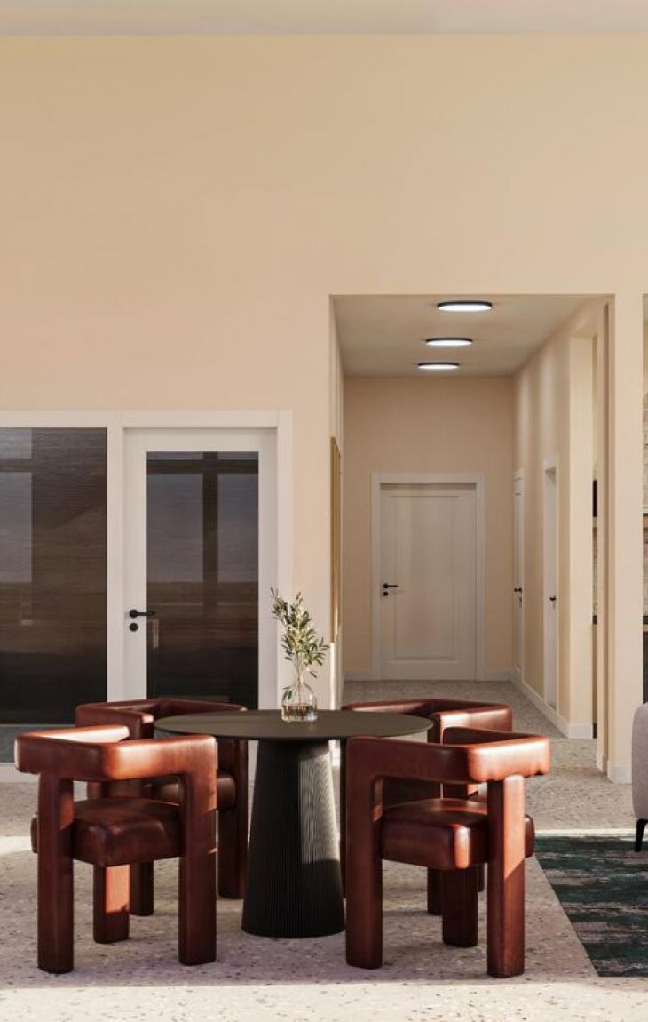 Modern lounge with workstations, round table, cozy seating, pendant lights, and large windows.